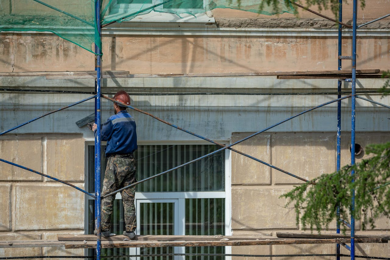 Crafting Captivating Headlines: Your awesome post title goes here A construction worker in a hard hat repairs a building facade on scaffolding in an urban setting.